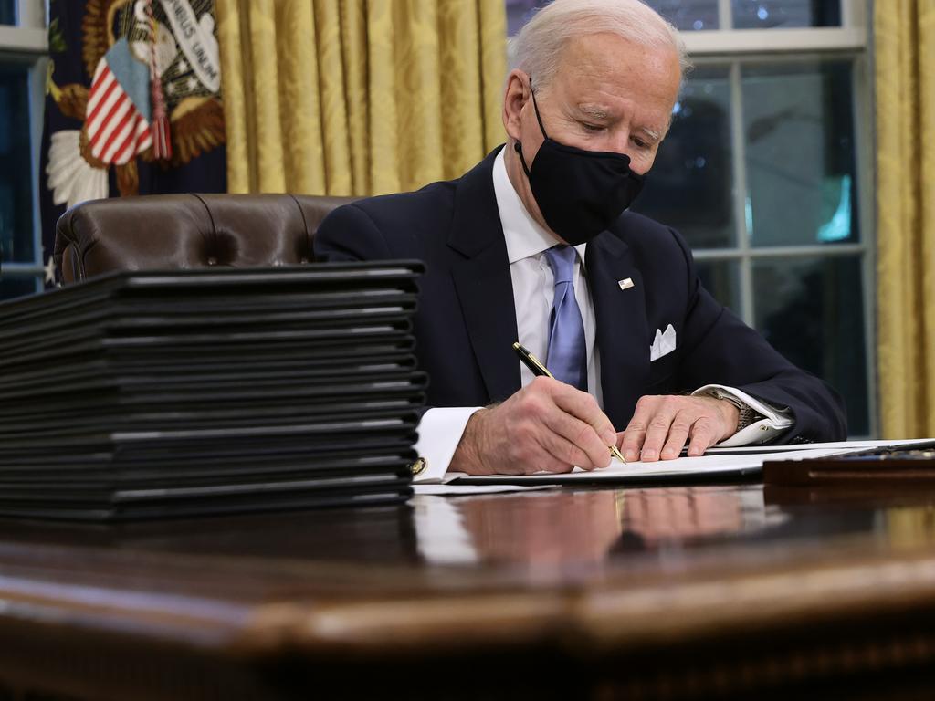 US President Joe Biden signs a series of executive orders at the Resolute Desk in the Oval Office just hours after his inauguration. Picture: Getty