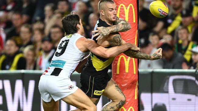 Dustin Martin of the Tigers handballs whilst being tackled by Jack Steele