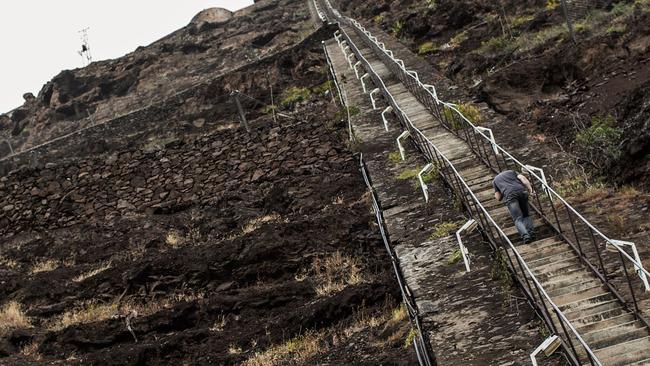 A man climbs the 699 steps of Jacob's ladder in Jamestown the capitol in the tropical island of Saint Helena, in the South Atlantic Ocean and part of the British Overseas Territory on October 15, 2017. After five years of construction, controversy and embarrassing delays due to high winds, an airport built at a cost of £285 million (318 million euros) will welcome its first routine flight from Johannesburg. / AFP PHOTO / GIANLUIGI GUERCIA