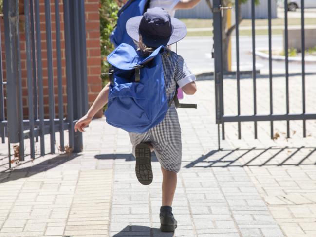 Two school children running out the school gate at the end of the day.