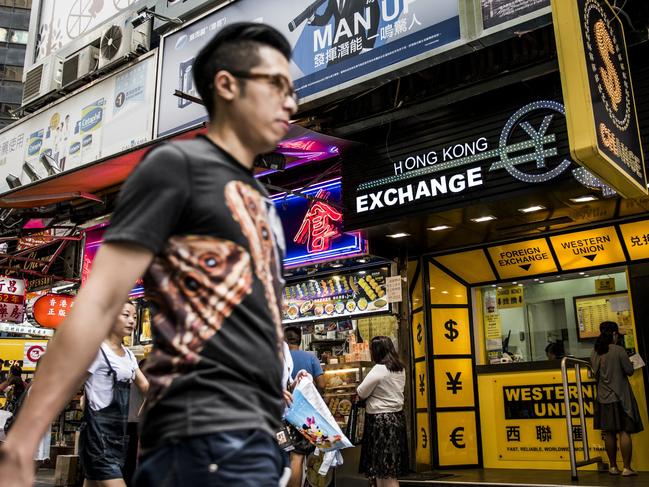 Pedestrians walk past a currency exchange store in Hong Kong, China, on Wednesday, Aug. 12, 2015. The yuan sank for a second day, spurring China's central bank to intervene as the biggest rout since 1994 tested the government's resolve to give market forces more sway in determining the exchange rate. Photographer: Xaume Olleros/Bloomberg