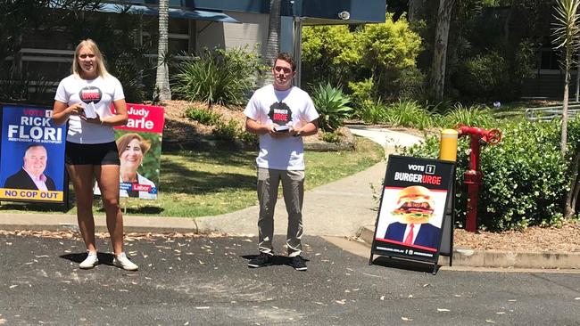 Burger Urge workers hand out "how to vote" cards offering free chips at the Ashmore State School polling booth. Picture: Lea Emery