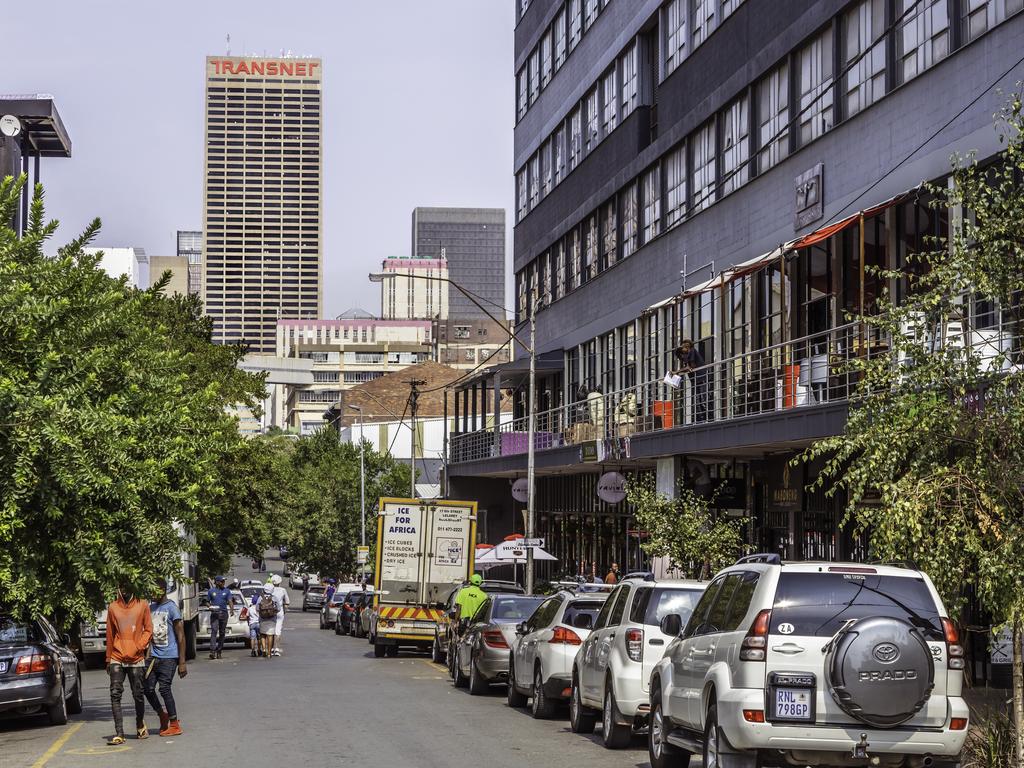 Cityscape of Johannesburg taken from Maboneng with tourists, pedestrians, vehicles and sidewalk cafes. Maboneng meaning 'a place of light' is a precinct of Johannesburg city and regeneration development in the city centre attracting new business, arts and culture.