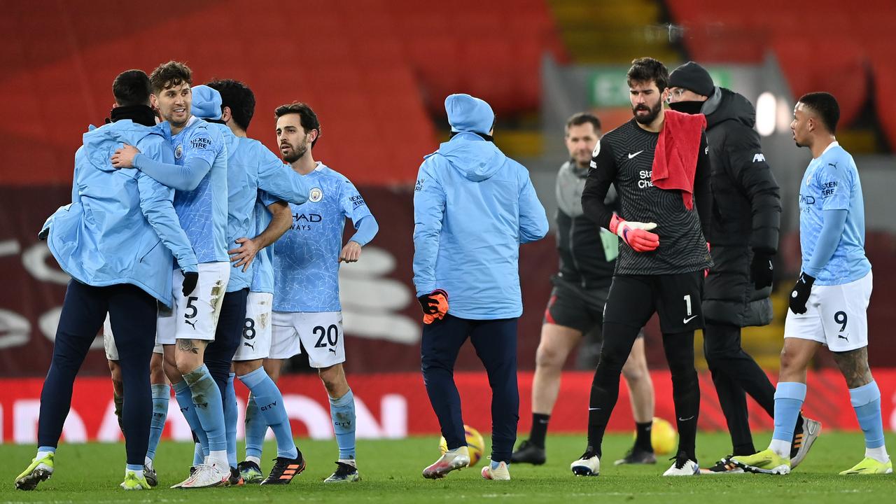 John Stones of Manchester City celebrates victory with teammates as Alisson Becker of Liverpool looks dejected. (Photo by Laurence Griffiths/Getty Images)