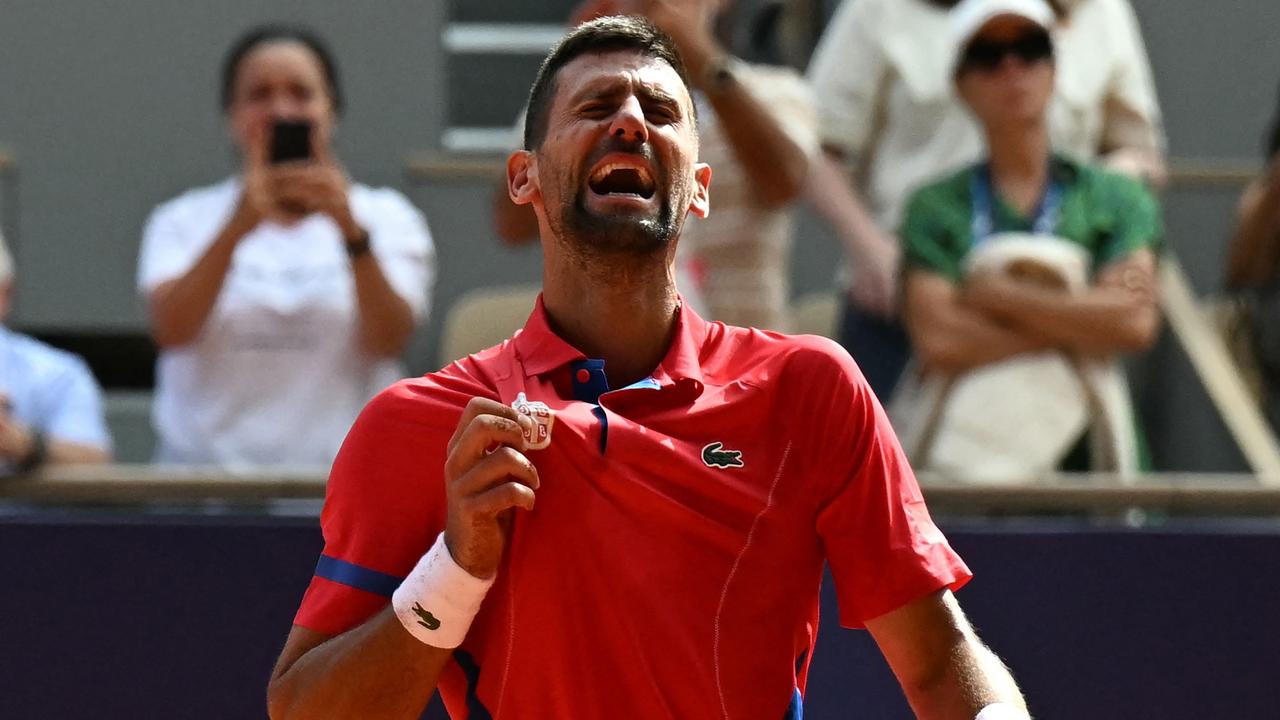 Serbia's Novak Djokovic celebrates holding his country's badge after beating Spain's Carlos Alcaraz in their men's singles final tennis match on Court Philippe-Chatrier at the Roland-Garros Stadium during the Paris 2024 Olympic Games, in Paris on August 4, 2024. (Photo by Patricia DE MELO MOREIRA / AFP)