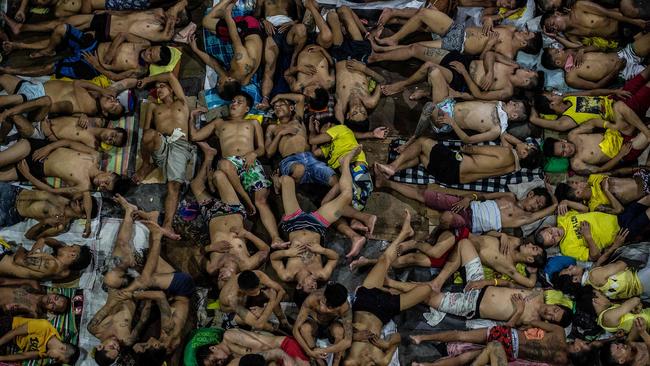 Inmates sleep on the ground of an open air basketball court inside the Quezon City jail at night in Manila. There are 3800 inmates at the jail, which was built six decades ago to house 800. Picture: Ayee Macaraig