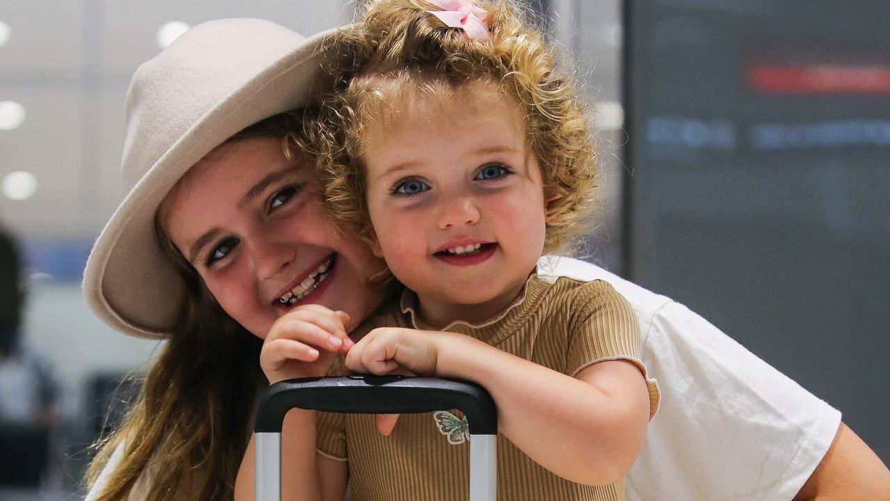 One-year-old Harper Duggan, who’s birthday is New Year’s Eve, is seen with her older sister Mackenzie Duggan at the baggage terminal at the Domestic Airport in Sydney. Picture: NCA Newswire / Gaye Gerard