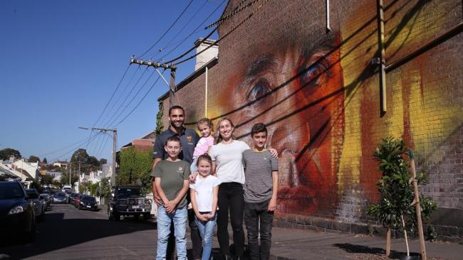 Shaun Burgoyne poses in front of his wall portrait in Richmond with wife Amy and kids Ky, Nixie, Leni and Percy.