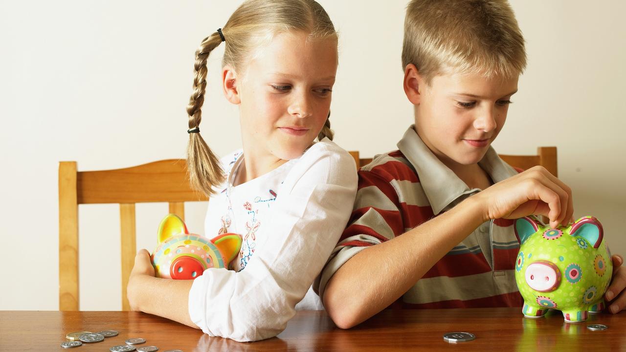 Girl (10-12) watching twin brother drop coin into piggy bank
