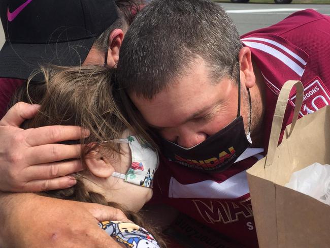 Bonnie, 8, embraces parents Boyd and Kathy McNamara across the border.