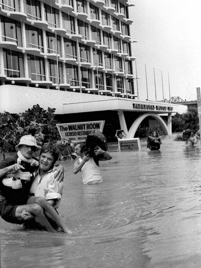 Flooding outside the Parkroyal Hotel Brisbane during the 1974 floods forces visitors to carry their luggage and others to drier ground. pic/McLachlan. weather qld floods