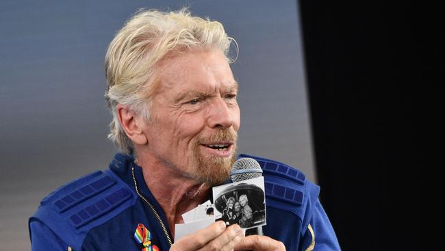 Sir Richard Branson holds up photos that he brought with him into space, as he speaks after flying into space aboard a Virgin Galactic vessel, a voyage he described as the “xperience of a lifetime”.