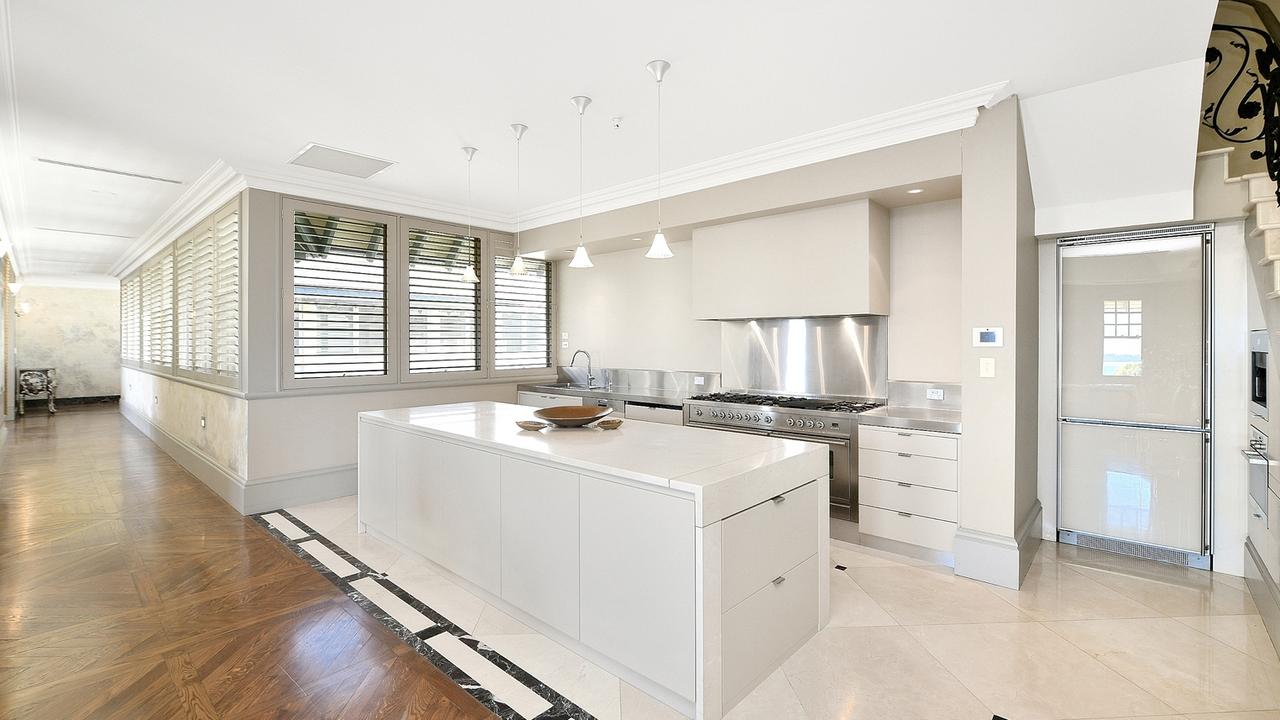 The kitchen features modern appliances, a large central island bench and marble surfaces.