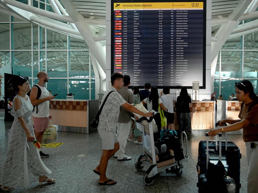 Passengers look at an electronic board displaying cancelled flights at the Ngurah Rai International Airport. Picture: AFP