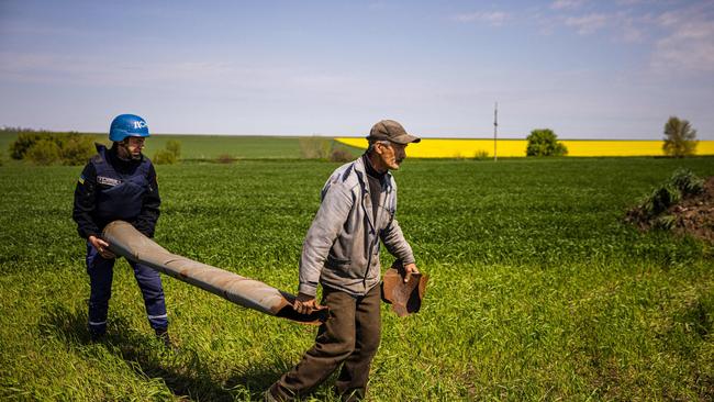 A farmer and a member of a de-mining team carry away an unexploded missile during planting season. Picture: AFP