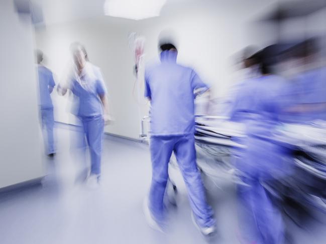 Doctors and nurses pulling hospital trolley,