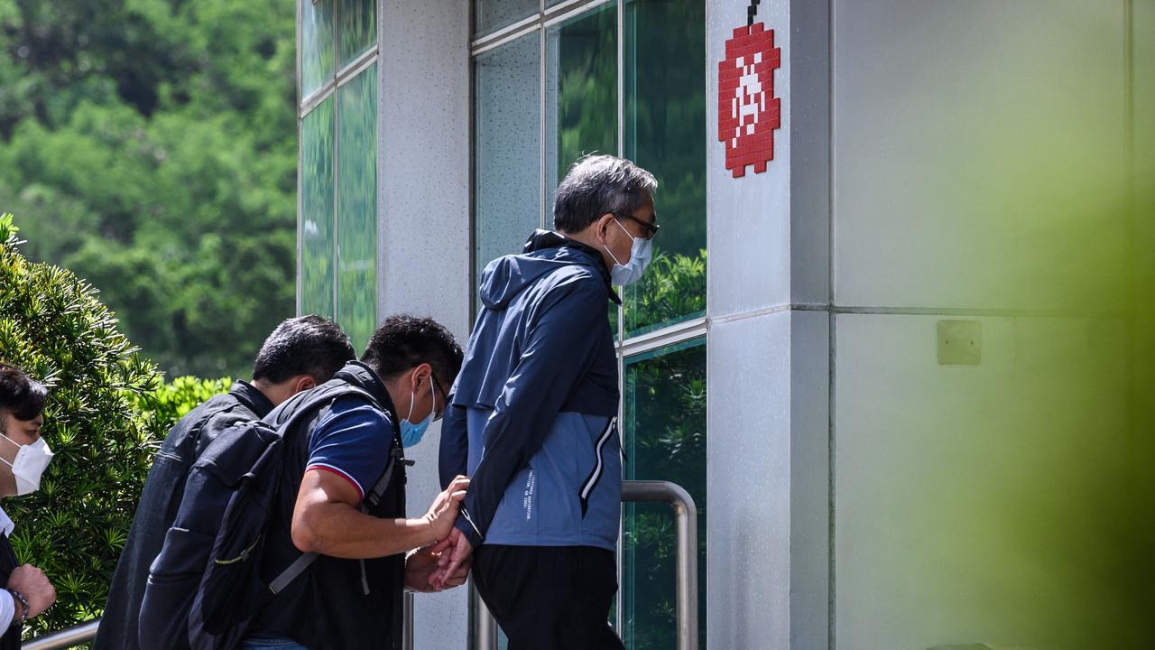 Cheung Kim Hung (C), CEO and executive director of Next Digital limited, is escorted by police into the offices of the local Apple Daily newspaper in Hong Kong.