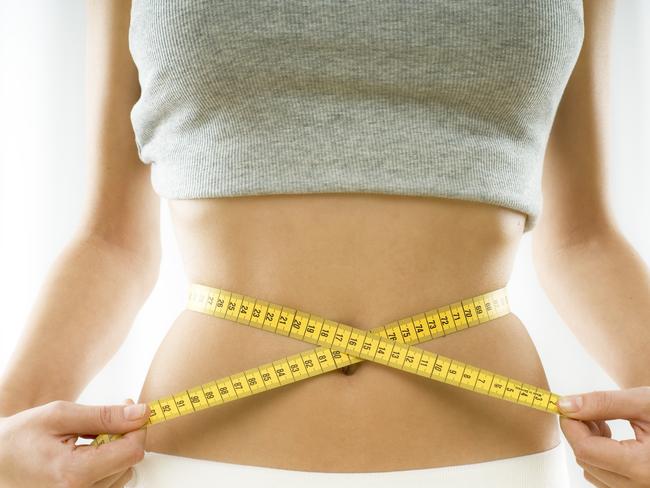 mid section view of a woman measuring her waist