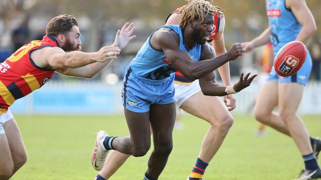 Sturt’s Martin Frederick dishes out a handpass under pressure from Crow Isaya McKenzie at Unley Oval on Saturday. Picture: SANFL Image/David Mariuz