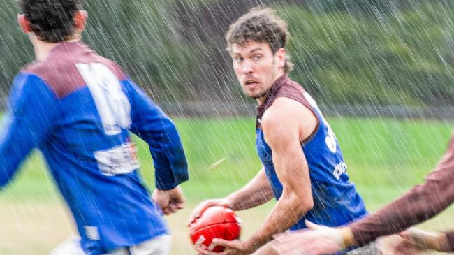 Tom Feldgen with the ball for Old Peninsula as rain tumbles down. Picture: Anthony Pearce