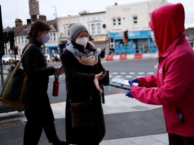 Volunteers hand out boxes of Covid-19 rapid antigen tests in London. The UK will roll out its fourth Covid jab this week. Picture: AFP