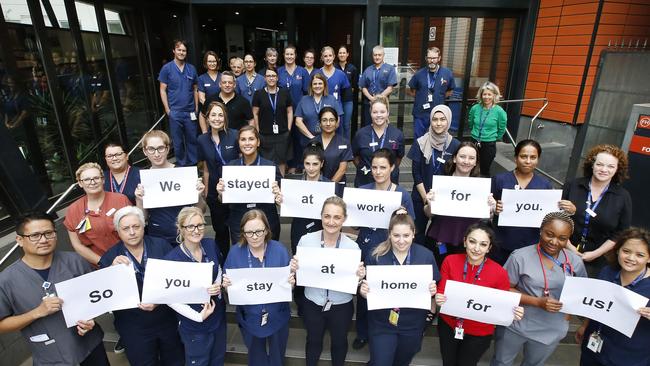 Royal Melbourne Hospital staff gather outside the main entrance urging people top stay at home. Picture: David Caird