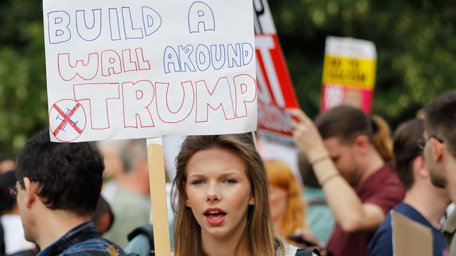 Protesters gather with placards at a barrier set up to block access to the US ambassador's residence, Winfield House, in Regents Park in London. Photo: AFP