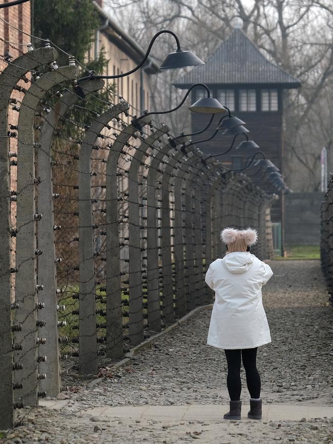 A visitor walks among barbed wire at the former Auschwitz I concentration camp.