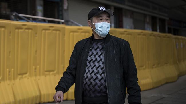 A man wearing a mask walks past a makeshift barricade in Wuhan. Picture: Getty Images