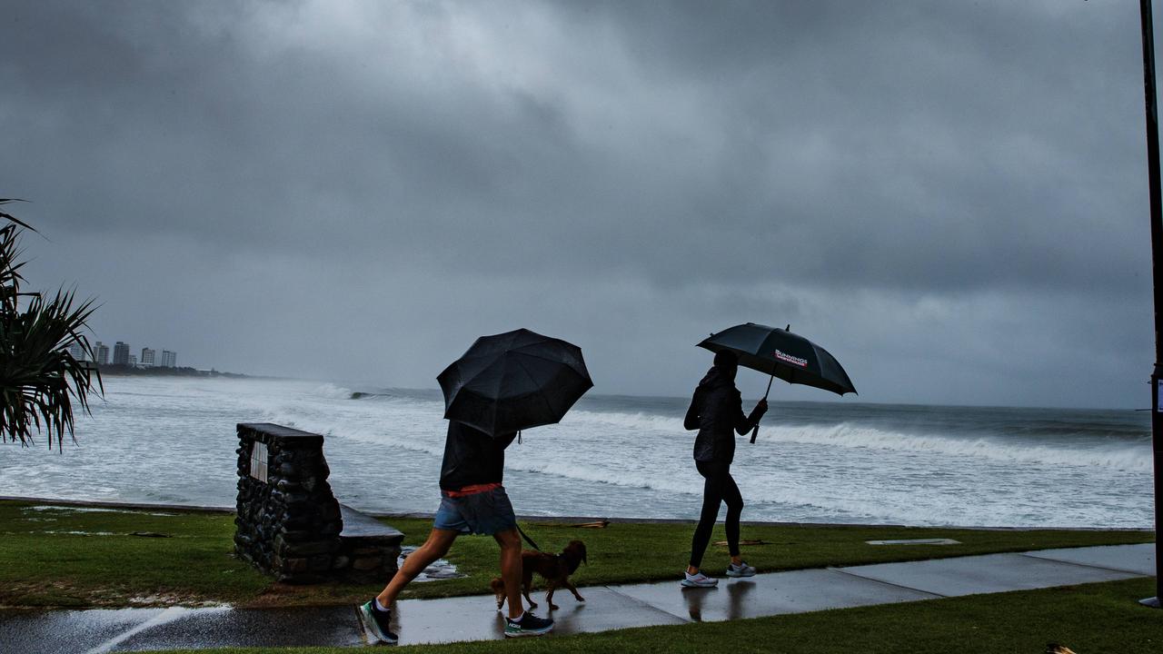 Morning walker and surfers brave the rain at Alexandra Headland on Sunday as an the effects of an east coast low hit South East Queensland. Picture: Lachie Millard