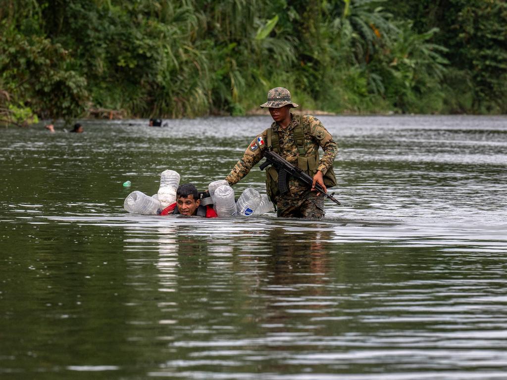 A Venezuelan migrant is helped by a member of Panama’s border patrol in Darien province. Picture: Luis Acosta/AFP