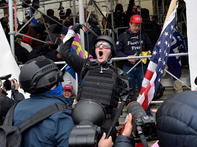 (FILES) In this file photo taken on January 06, 2021, a man calls on people to raid the building as Trump supporters clash with police and security forces as they try to storm the US Capitol in Washington D.C. - One year after supporters of Donald Trump stormed the US Capitol and shut down Congress, Americans still await a reckoning on the unprecedented challenge to the country's democracy. Was it a simple protest-turned-riot? An insurrection? A coup attempt plotted by Trump? Videos from January 6, 2021 bear witness to the violence wrought in the former president's name. Attackers beating security officers with iron bars and clubs. A policeman crushed in a doorway, howling in pain. Rioters clad in assault gear chanting "Hang Mike Pence," while the vice president and Democratic and Republican lawmakers flee. A woman shot to death in a Capitol hallway. Americans were stunned by the hours-long assault, and so was much of the world, accustomed to seeing the United States as a model of stable democracy. One year later, the brazen attempt to prevent Democrat Joe Biden from taking office after his victory in the November 2020 presidential election needs an accounting. (Photo by Joseph Prezioso / AFP)