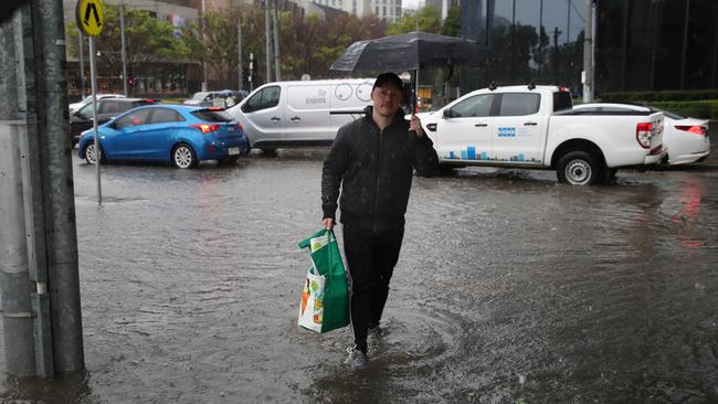 Pedestrians wade through the flooding in Southbank. Picture: David Crosling