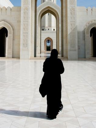 Woman in Abaya Cloak walking towards Archway of Grand Mosque