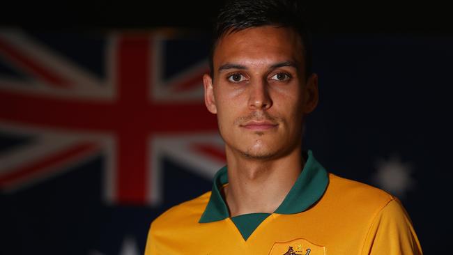 Trent Sainsbury of Australia poses in his Socceroos jersey in front of the flag.