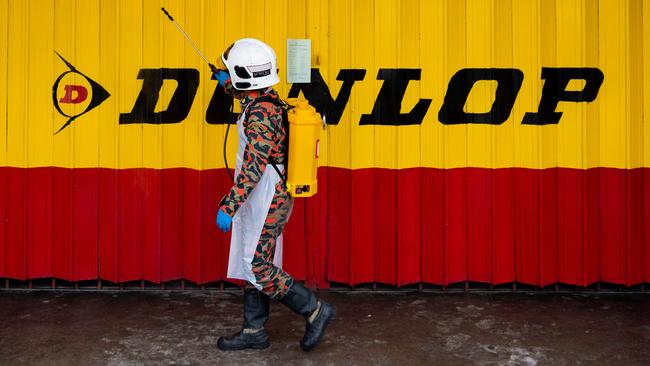 A member of Malaysia Fire and Rescue Department sprays disinfectant at a closed shop in Karak, outside Kuala Lumpur, at the weekend. Picture: AFP