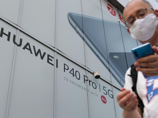 A pedestrian walks under an advertisement for Chinese telecoms company Huawei's latest phone in Tokyo's electric town Akihabara on June 26, 2020. (Photo by Kazuhiro NOGI / AFP)