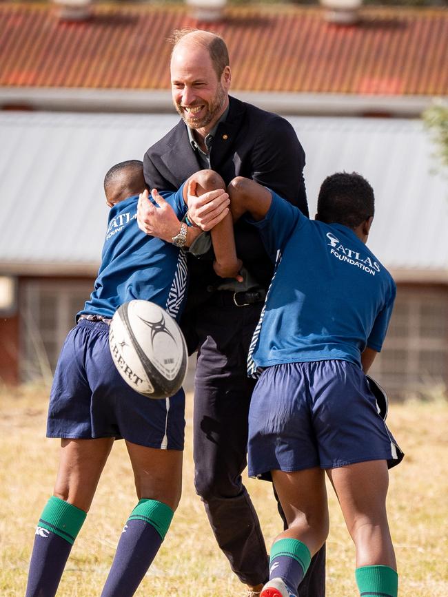 School children tackle the prince in a friendly game. Picture: Getty Images