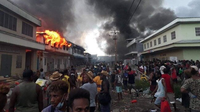 Large crowds take to Honiara’s streets on Thursday as buildings burn in the Chinatown district of the Solomon Islands capital.