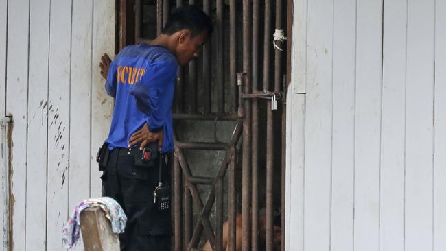 A security guard talks to detainees inside a cell at the compound of a fishing company in Benjina, Indonesia. The imprisoned men were considered slaves who might run away.