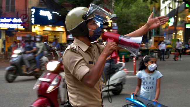 A policeman tries to disperse shoppers gathered in a commercial area in Bangalore as residents prepare for a lockdown to contain the surge of coronavirus cases. Picture: AFP