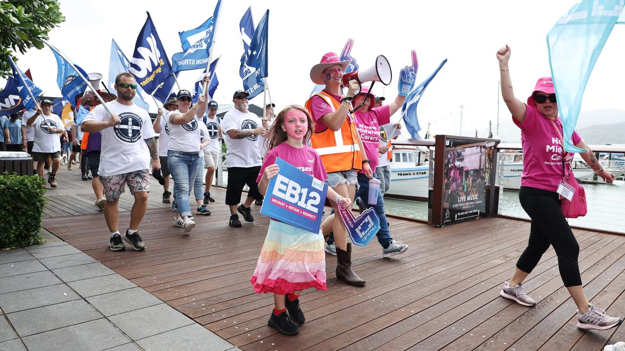 Lilith Ryan, 8, walks with her mother, Suri Hobday, from the Queensland Nurses and Midwives Union in the annual Labour Day march in Cairns City. Picture: Brendan Radke