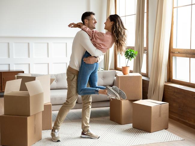 Happy young husband lifting excited wife celebrating moving day with cardboard boxes, proud overjoyed family couple first time home buyers renters owners having fun enjoy relocation, mortgage concept istock image