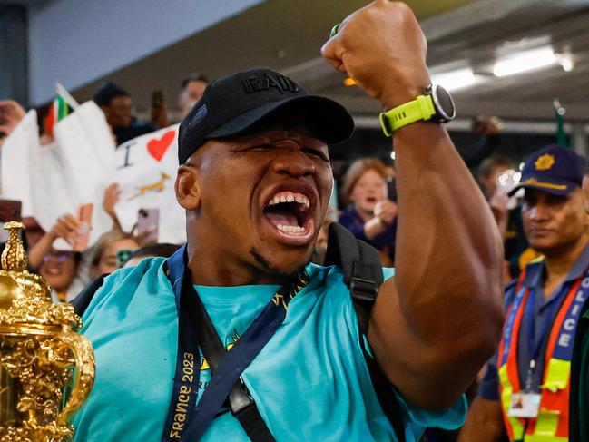 South Africa's hooker Bongi Mbonambi celebrates as he holds the Webb Ellis Cup upon the South African rugby team's arrival at the OR Tambo International airport in Ekurhuleni on October 31, 2023, after they won the France 2023 Rugby World Cup final match against New Zealand. (Photo by PHILL MAGAKOE / AFP)