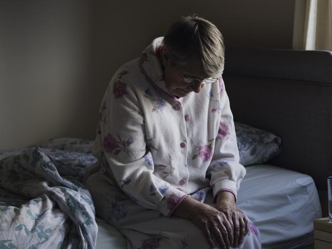 BAD AGED CARE:   A shot of a senior woman sitting on the side of her bed with her head down looking sad. She looks like she has just woken up as is dressed in nightwear.