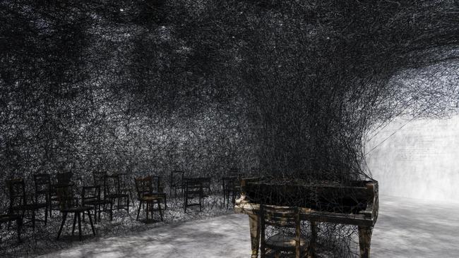 Chiharu Shiota Japan b.1972 In Silence 2002/2022 Burnt piano, burnt chairs, Alcantara black thread Dimensions variable Production support: Alcantara S.p.A.Installation view: ‘Chiharu Shiota: The Soul Trembles’, Gallery of Modern Art, Brisbane, 2022© Chiharu Shiota Photograph: Natasha Harth, QAGOMA