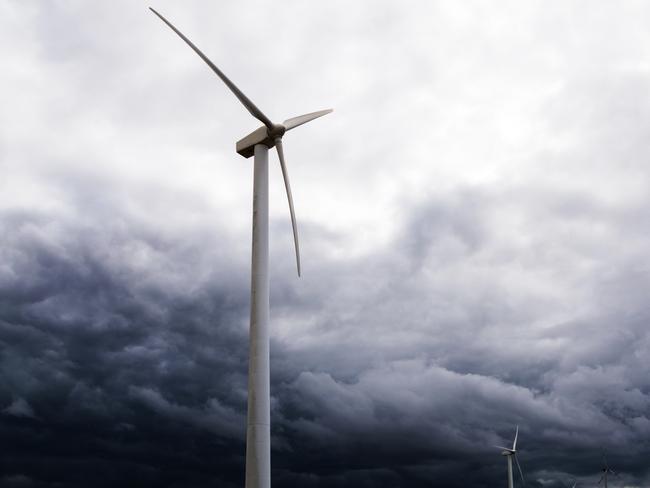 wind turbines against dark clouds in the upcoming storm, concept for renewable energy or increasing complications by the protest of wind power opponents, selected focus