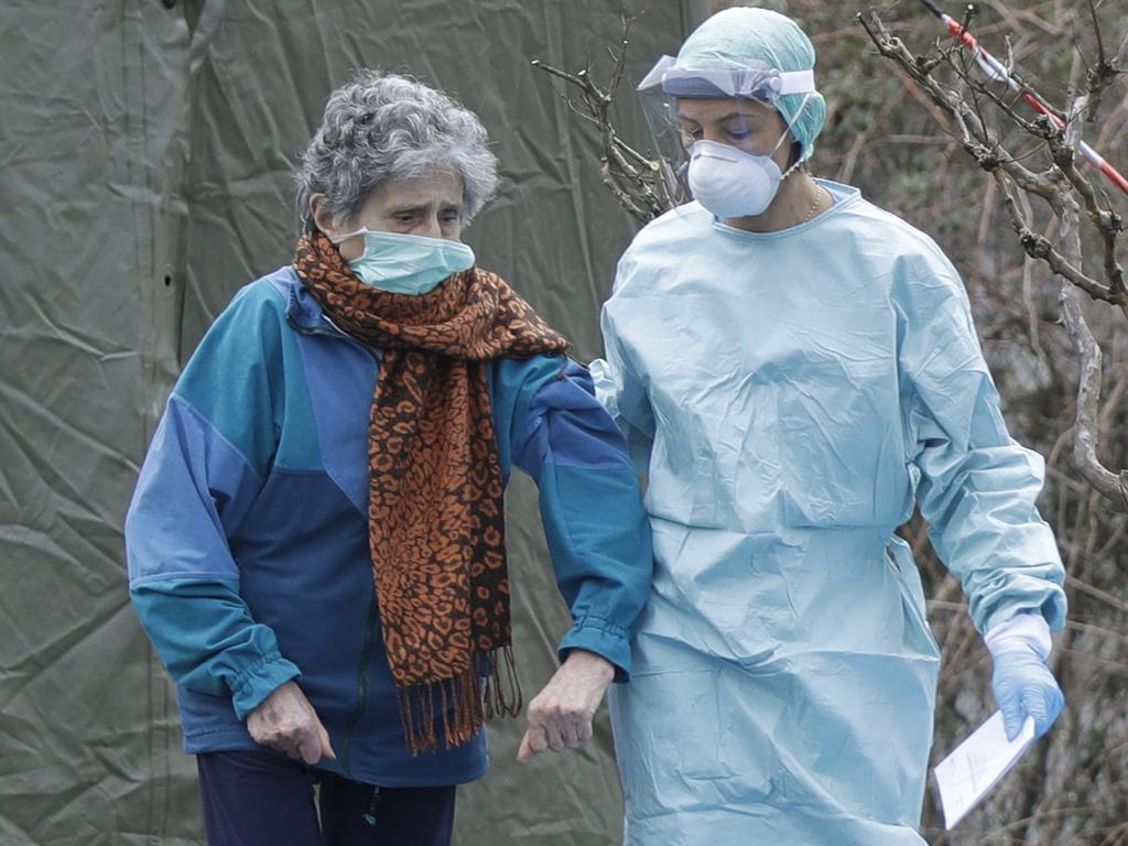 An elderly patient is helped by a doctor at one of the emergency structures that were set up to ease procedures at the Brescia hospital, northern Italy. Picture: AP Photo/Luca Bruno.