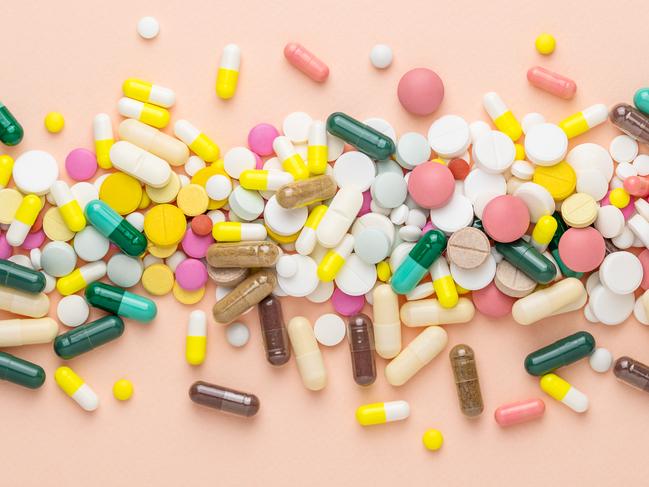 Many different pills on pink background. Prescription pills and vitamins. Flat lay and space for text