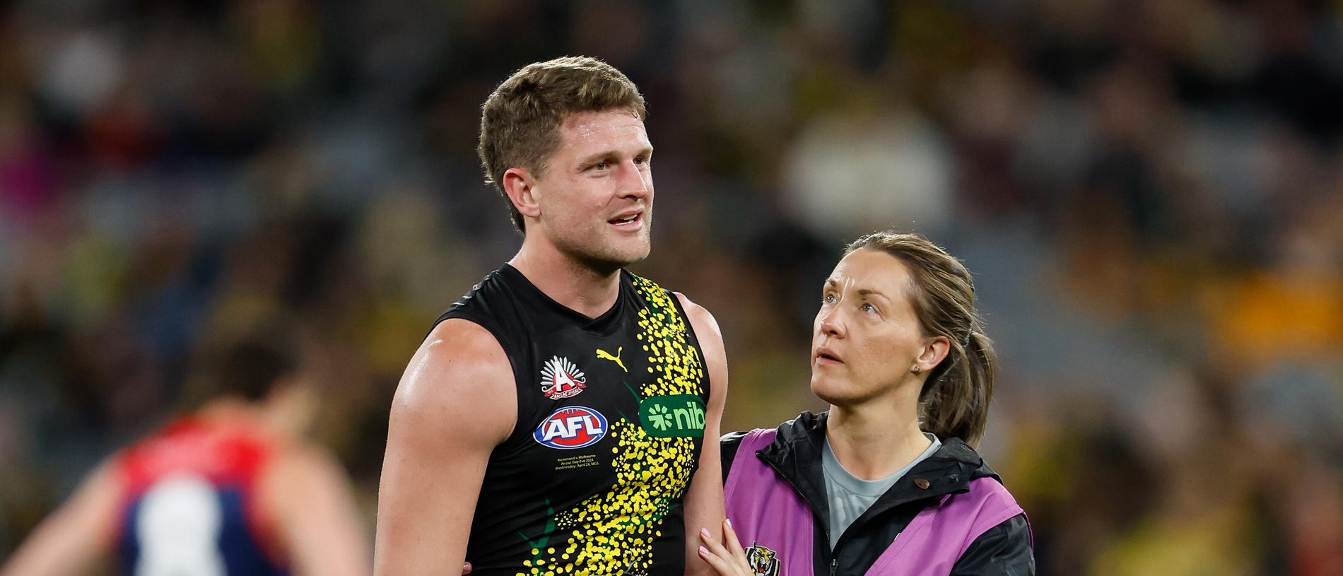MELBOURNE, AUSTRALIA - APRIL 24: Jacob Hopper of the Tigers is seen to by medical staff during the 2024 AFL Round 07 match between the Richmond Tigers and the Melbourne Demons at the Melbourne Cricket Ground on April 24, 2024 in Melbourne, Australia. (Photo by Dylan Burns/AFL Photos via Getty Images)
